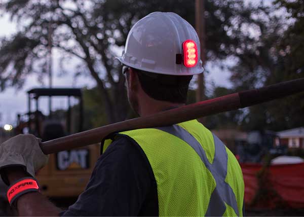 Construction worker wearing a high visibility vest and hard hat safety light at a job site
